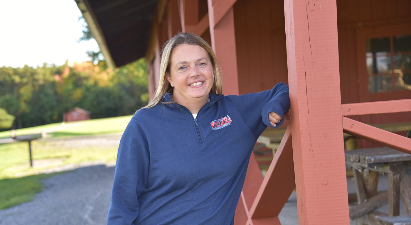 Meg Fuller smiling, leaning on a red barn post